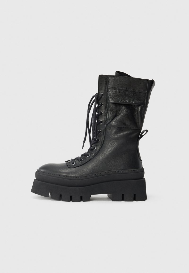 Schwarze Lederkampfstiefel mit hohem Schaft, schnüren vorne, strukturierten Akzenten, dicker Sohle und genähten Details. Verfügt über eine hintere Zuglasche.