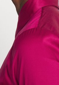 Tætsiddende bluse i levende magenta satin med en glat tekstur, der har en struktureret krave og en skræddersyet silhuet.