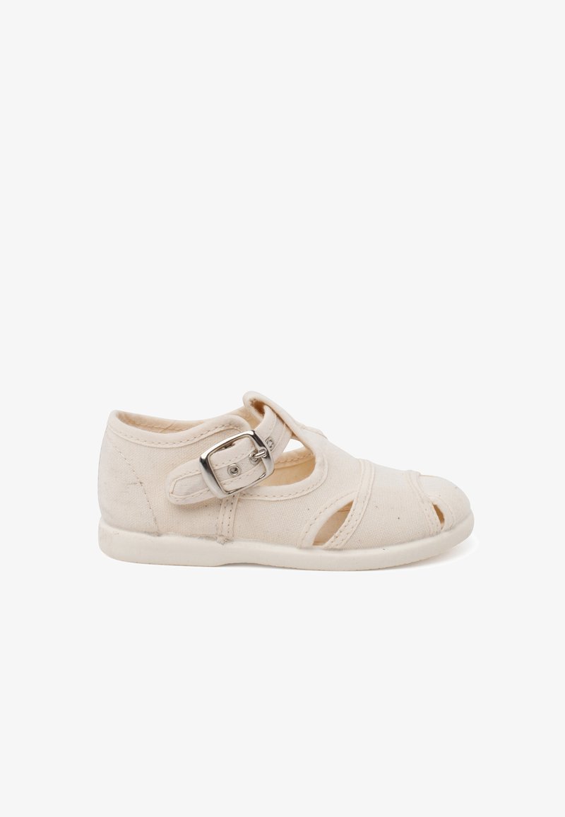 Hellbeige Leinenschuhe mit abgerundetem Zehenbereich, seitlichen Ausschnitten und einem silbernen Schnallenriemen. Flache Sohle und strukturierte Stoffoberfläche.