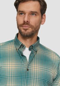 Groen en beige geruit shirt met een button-down kraag, voorzien van een gestructureerde stof en bruine knopen bij de kraag en manchetten.