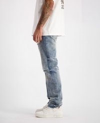 Lichtblauwe denim jeans met een slim fit en lichte vervaging. Draag ze met witte sneakers, met een platte zool en vetersluiting.