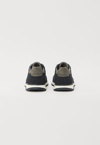 Chaussures de sport bleu marine avec des accents gris, en mesh et daim, col rembourré, semelle intermédiaire blanche et semelle extérieure en caoutchouc. Vue arrière présentée.