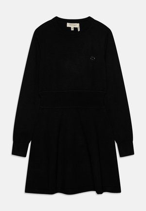 Schwarzes Strickkleid mit langen Ärmeln, rundem Ausschnitt, tailliertem Oberteil und ausgestelltem Rock. Verfügt über ein kleines Logodetail auf der Brust.