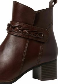 Hnědá kožená kotníková bota s detailním opletením, čtveratou špičkou, prošívanými akcenty a blokovým podpatkem s texturovaným povrchem.