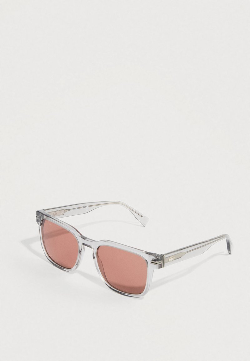 Klar akryl solbriller med rektangulære stel, der har rosa-tintede linser og sølvdetaljer på stængerne. Overfladen har en tekstureret detalje.
