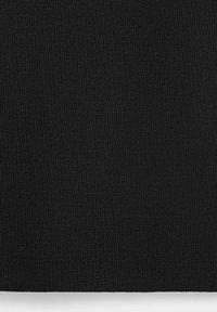 Tissu tricoté noir avec une texture côtelée serrée et uniforme s'étendant sur toute la surface visible.