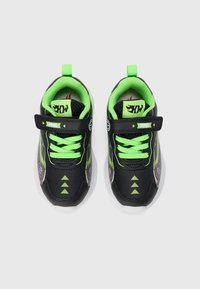 Chaussures de sport noires avec accents vert néon, en matériau en maille, design à lacets, fermeture par sangle et motifs en flèche sur le bout.