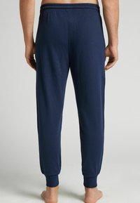 Heren navy katoenen joggers met elastische tailleband, geribbelde manchetten en een gladde textuur, met een ontspannen pasvorm.