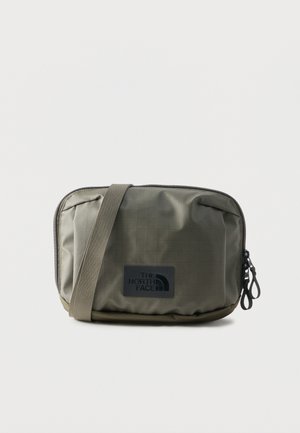 Olive green rectangular crossbody bag with black The North Face logo patch and dual zipper closure on a plain background.
