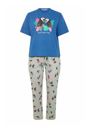 Blauw shirt met korte mouwen met twee toekans en tropische bladeren boven een grijze broek bedrukt met kleurrijke toekans en bladvormen.