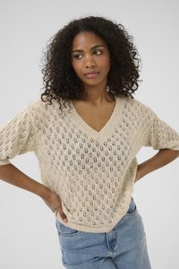Beige strikket kortærmet sweater med V-hals, åbent vævemønster med bladmotiver og loose fit. Båret med lyseblå jeans.