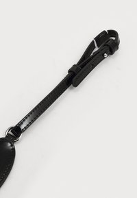 Sort læderrem med blank finish, præget med stikninger og metalhardware-spænde. Remmen er justerbar og har en flad form.