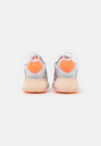 Sports shoes with a light gray mesh upper, prominent orange heel accents, and a textured cream sole. Features pull tabs for easy wear.