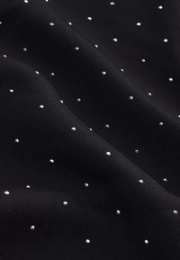 Black fabric with a ribbed texture, adorned with scattered silver studs in various sizes. The composition is soft and slightly glossy.