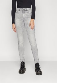 Höga grå skinny jeans med en blekt finish och subtila slitage. Kombineras med svarta snörstövlar med en kraftig sula.
