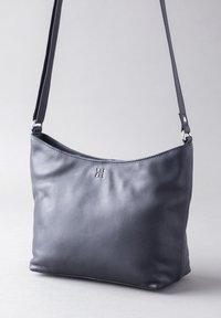 Leather shoulder bag in dark gray with a smooth texture, curved design, and a debossed logo. Includes a long strap and zip closure.