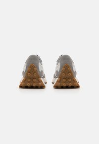 Sneaker grigie e bianche con suola in gomma triangolare, collarino imbottito e accenti bianchi. Caratterizzano una chiusura con lacci e tomaia testurizzata.