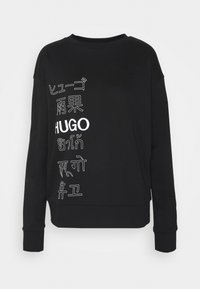 Sudadera negra de manga larga con texto multilingüe blanco que incluye "HUGO" y otros caracteres impresos verticalmente en el lado izquierdo frontal.