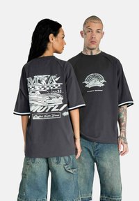 Dark gray oversized T-shirt with short sleeves and contrasting white trim. Graphic designs on front and back feature automotive motifs.