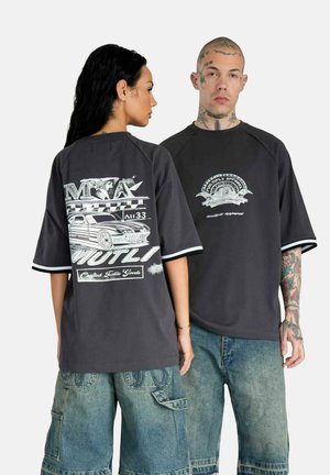 Dark gray oversized T-shirt with short sleeves and contrasting white trim. Graphic designs on front and back feature automotive motifs.