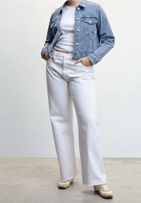 Kurtka dżinsowa w jasnoniebieskim kolorze, z kieszeniami na piersiach, zestawiona z białymi spodniami z wysokim stanem. Codzienne sneakersy z beżowymi akcentami dopełniają stylizację.