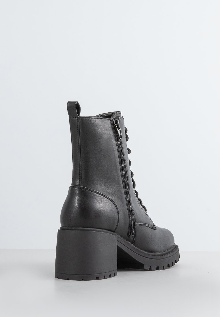 Schwarze Leder-Stiefel bis Knöchel mit einem stabilen Absatz, ausgestattet mit einer Schnürung vorne, einem seitlichen Reißverschluss und einer strukturierten Gummisohle für besseren Halt.