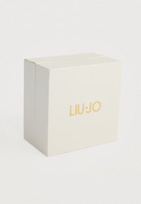Λευκό κουτί δώρου με υφή, τετράγωνο σχήμα, με το χρυσό λογότυπο "LIU•JO" στο μπροστινό μέρος. Απλός και κομψός σχεδιασμός.