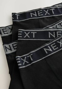 Fekete alsónemű széles derékrésszel, amelyen szürke betűkkel "NEXT" felirat található. Simára kidolgozott anyag, egyszerű és funkcionális dizájnnal.