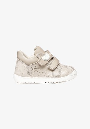 Scarpa da bambino beige chiaro con due cinturini in Velcro, motivi in rilievo di stelle e farfalle, e suola bianca flessibile.