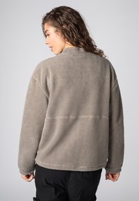 Fleece-Pullover in Hellgrau mit rundem Kragen, langen Ärmeln und einer weichen, strukturierten Oberfläche. Auffällige abgesteppten Naht an der Rückseite.