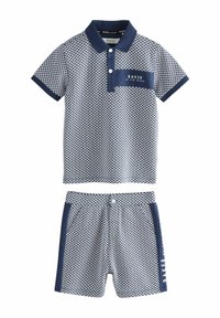 Marineblauwe en witte polo met honingraatpatroon, twee knopen en een borstzak; bijpassende shorts met zijaccenten en logo.