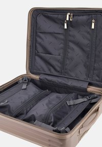 Hard-shell suitcase in beige with a gray interior. Features zippered compartments and straps for organization. Smooth texture, durable design.