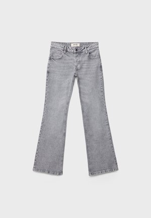 Svetlo sive kavbojke s ravnimi hlačnicami, z žepi spredaj in zadaj, z zankami za pas in zapiranjem na gumb, položene ravno na belem ozadju.