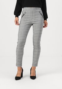 Gray plaid pants with a slim fit, featuring zippered pockets. Made of a smooth fabric with a structured texture. Heeled black shoes worn.