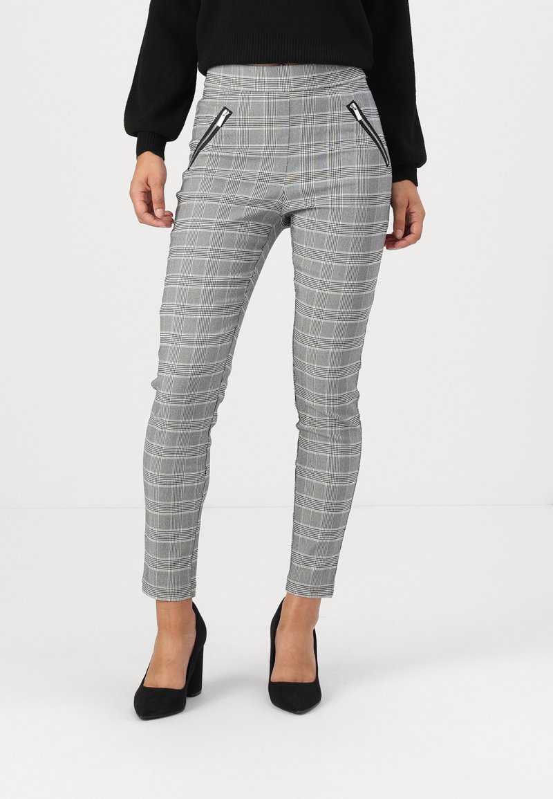 Gray plaid pants with a slim fit, featuring zippered pockets. Made of a smooth fabric with a structured texture. Heeled black shoes worn.