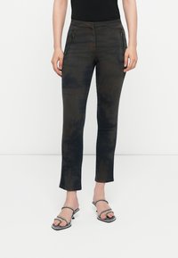 Black and grey tie-dye jeans with front zippered pockets, slim fit, and straight leg; worn with black heeled sandals.
