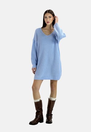 Robe en tricot bleu clair avec un col en V, des manches longues et une texture côtelée. Portée avec des bottes marron jusqu'aux genoux et des chaussettes crème.