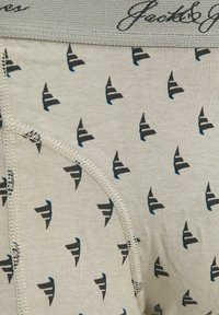 Ljust grå bomullsunderkläder med ett upprepande mönster av små blå och svarta geometriska former. Elastisk midjeband med varumärkesnamnet broderat.
