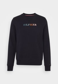 Svart sweatshirt med rund halsringning. Har "HILFIGER"-logotyp i flerfärgad brodyr. Ribbstickade muddar och fåll. Mjuk tygstruktur.