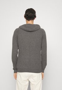 Graue Kapuzenjacke aus weichem Stoff, mit lockerer Passform und großer Kapuze. Das Design umfasst gerippte Bündchen und einen Saum für einen angenehmen Abschluss.