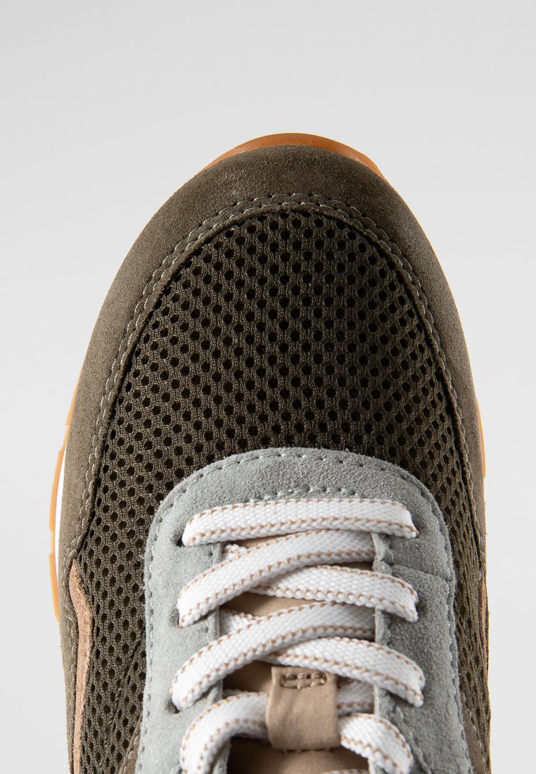 Chaussure de sport avec un dessus en maille vert foncé et des accents en daim gris, des lacets blancs et une semelle en caoutchouc brun clair.