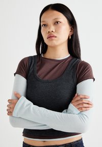 Layered tops featuring a dark gray ribbed tank and a brown short-sleeve shirt, with light blue long sleeves, smooth texture, and scoop neck.