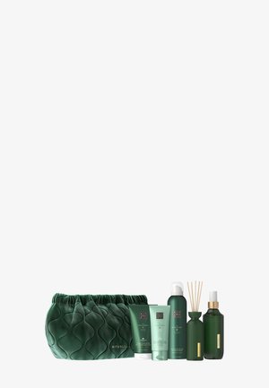 Borsa cosmetica in velluto verde con design trapuntato, accompagnata da tre tubetti verdi, due bottiglie e un diffusore di stuzzicadenti in tonalità verdi coordinate.