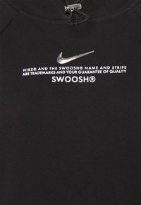 Černá mikina s kapucí s stříbrným logem Nike Swoosh. Obsahuje bílý text o ochranných známkách. Vyrobena z texturované, elastické látky.