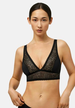 Bralette negro con diseño de escote en V profundo, superposición de encaje floral y borde festoneado a lo largo de los bordes, proporcionando un contraste texturizado.