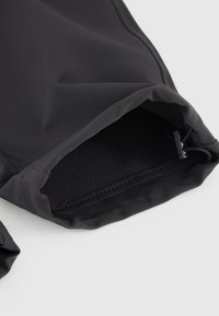 Svart prestandatygerärm med slät textur, elastisk mudd och dragsko för justerbar passform. Sömmar synliga.