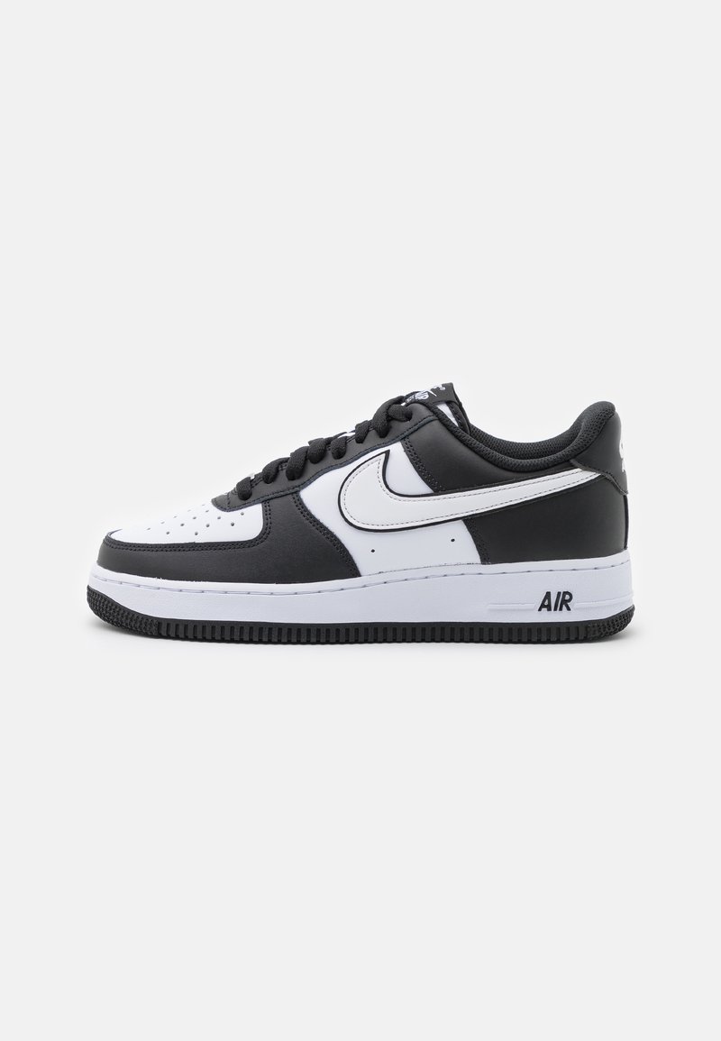 Baskets basses Nike Air Force 1 noir et blanc avec logo swoosh blanc, lacets noirs et semelle blanche avec texte « AIR » sur le côté.