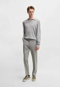 Gray long-sleeve polo shirt with a subtle sheen, paired with light gray tailored trousers and olive green sneakers with a textured surface.