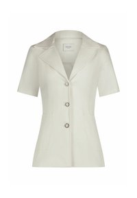 Lichtbeige blouse met korte mouwen en een halslijn met inkeping, drie knopen met zilverkleurige accenten en twee frontzakken. Textuurdesign van de stof.