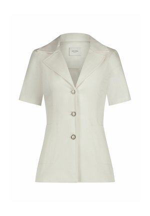 Hellbeige Bluse mit kurzen Ärmeln und einem eingeschnittenen Kragen, drei Knöpfen mit silbernen Akzenten und zwei vorderen Taschen. Strukturierter Stoffdesign.